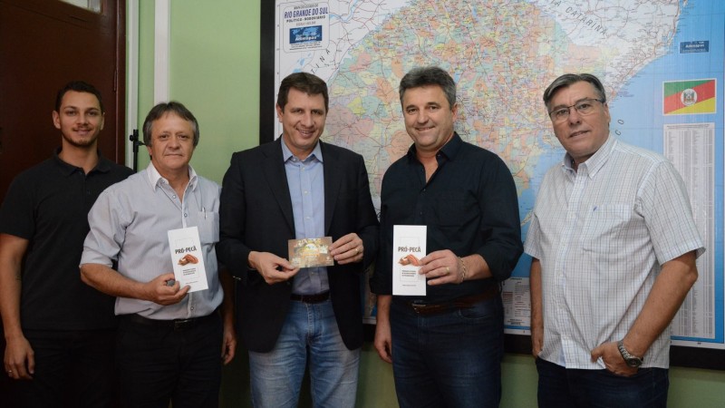 secretário e mais quatro servidores posam para foto com folder na mão