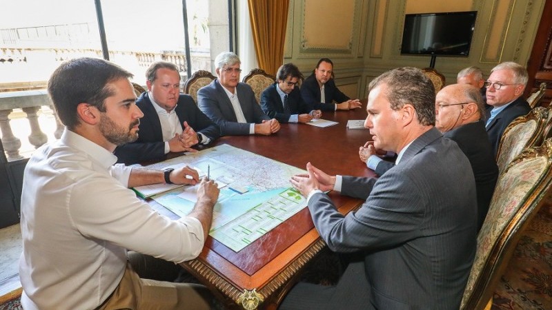 Governador e secretário em mesa de reunião com representantes do setor arrozeiro