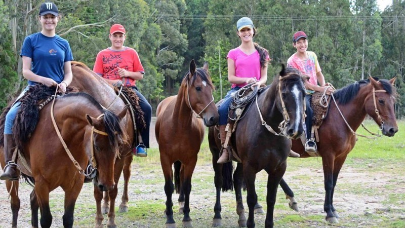 Quatro jovens andando a cavalo